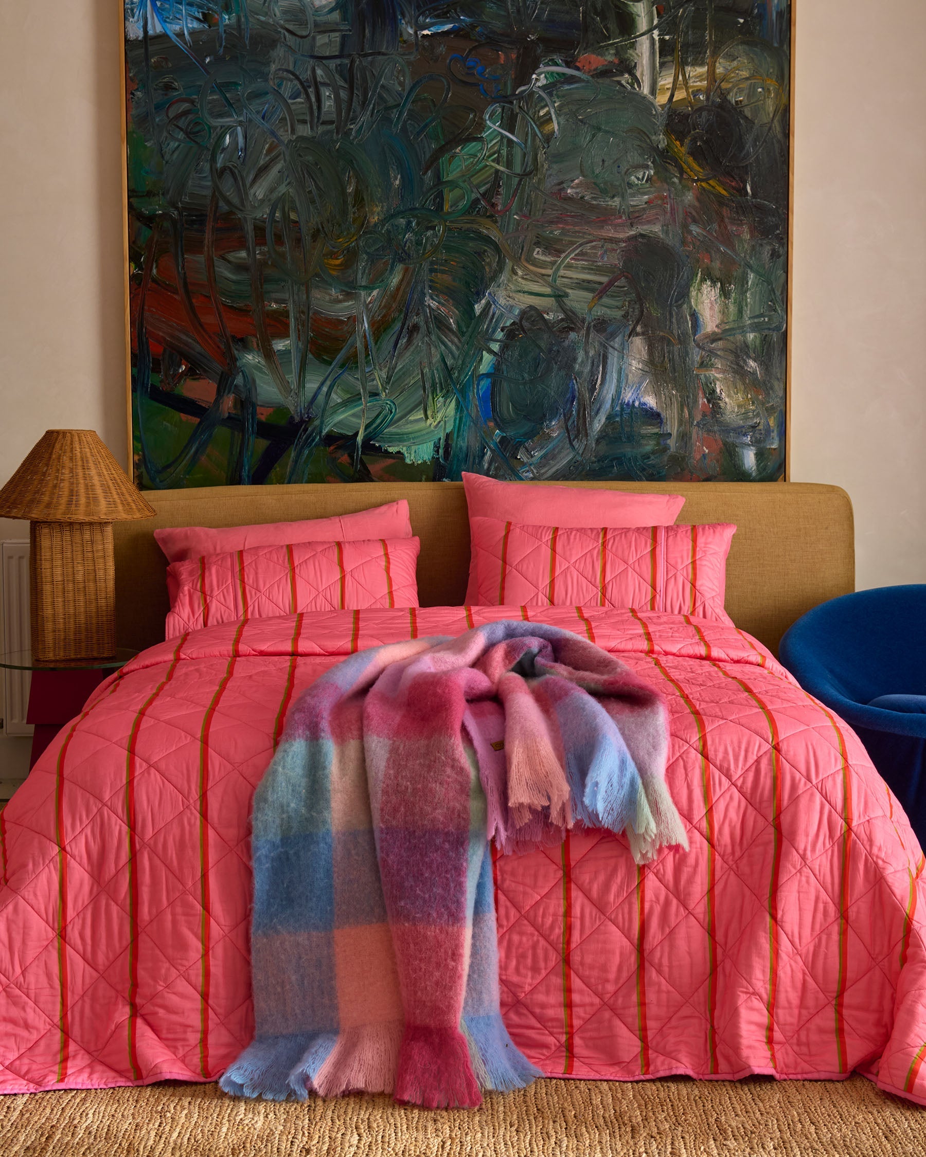 Styled bedroom scene with Wategos Soiree Stripe pink quilted bedspread and colorful plaid throw blanket