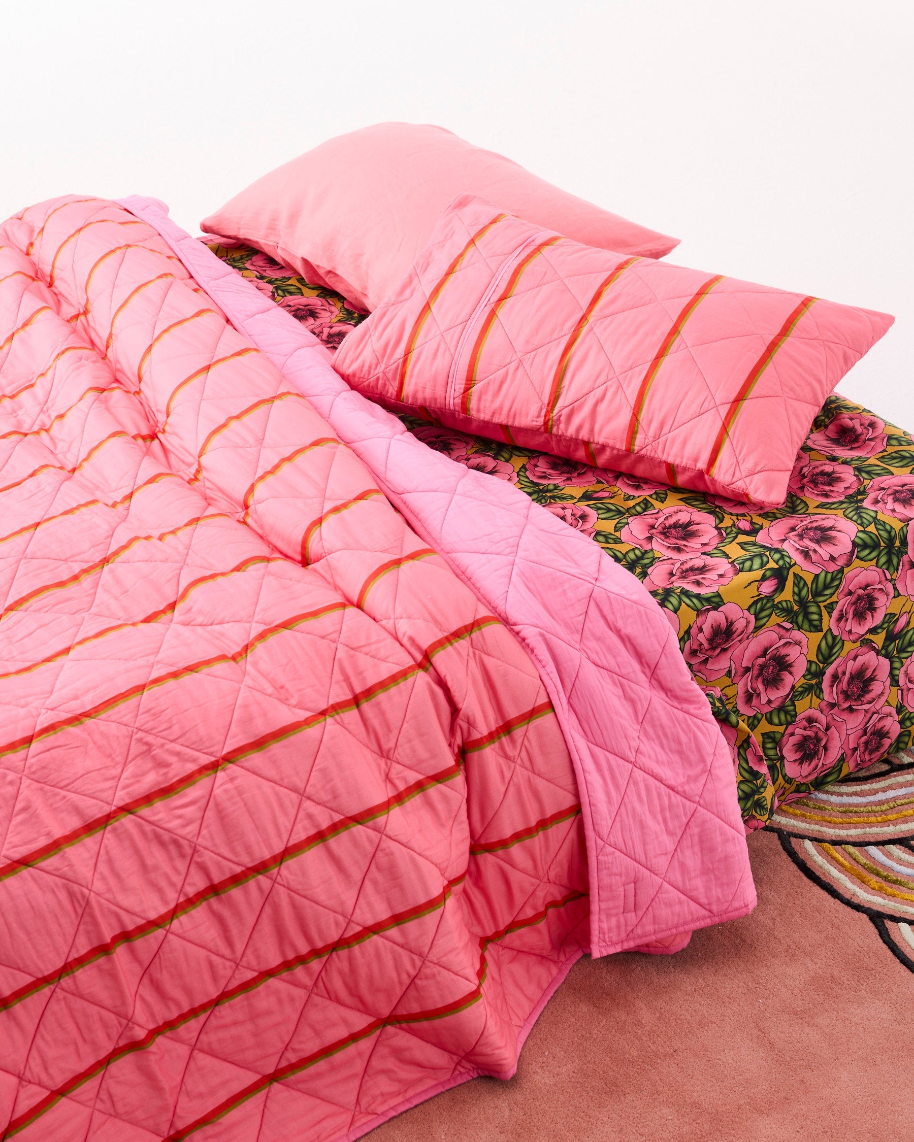 Wategos Soiree Stripe quilted bedspread folded showing pink organic cotton fabric and reverse floral pattern