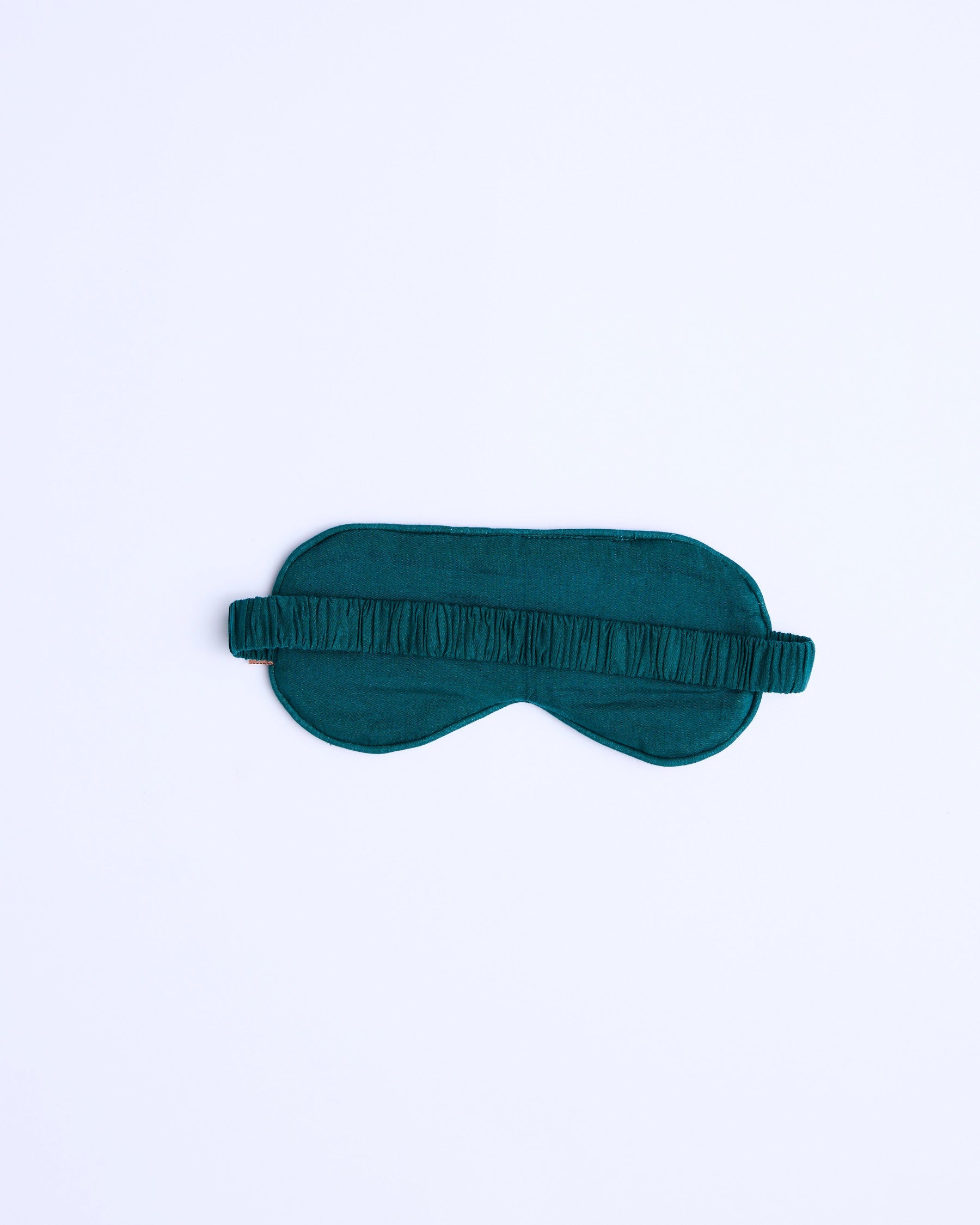 Flat lay of Kip & Co Wild Grape Eye Mask back side showing teal velvet fabric and adjustable elastic band