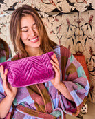 Model holding Kip Co Wild Grape Velvet Toiletry Bag showing quilted texture and luxurious feel