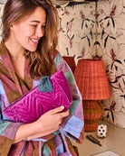 Close up of model with Wild Grape Velvet Toiletry Bag featuring teal tassel detail by Kip Co