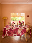 Full view of Wild Pansy Pink Tablecloth covering round dining table in warm dining room