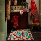 Moonlight Winona Bath Mat with cream ground and red floral tufted design on a dark tiled bathroom floor