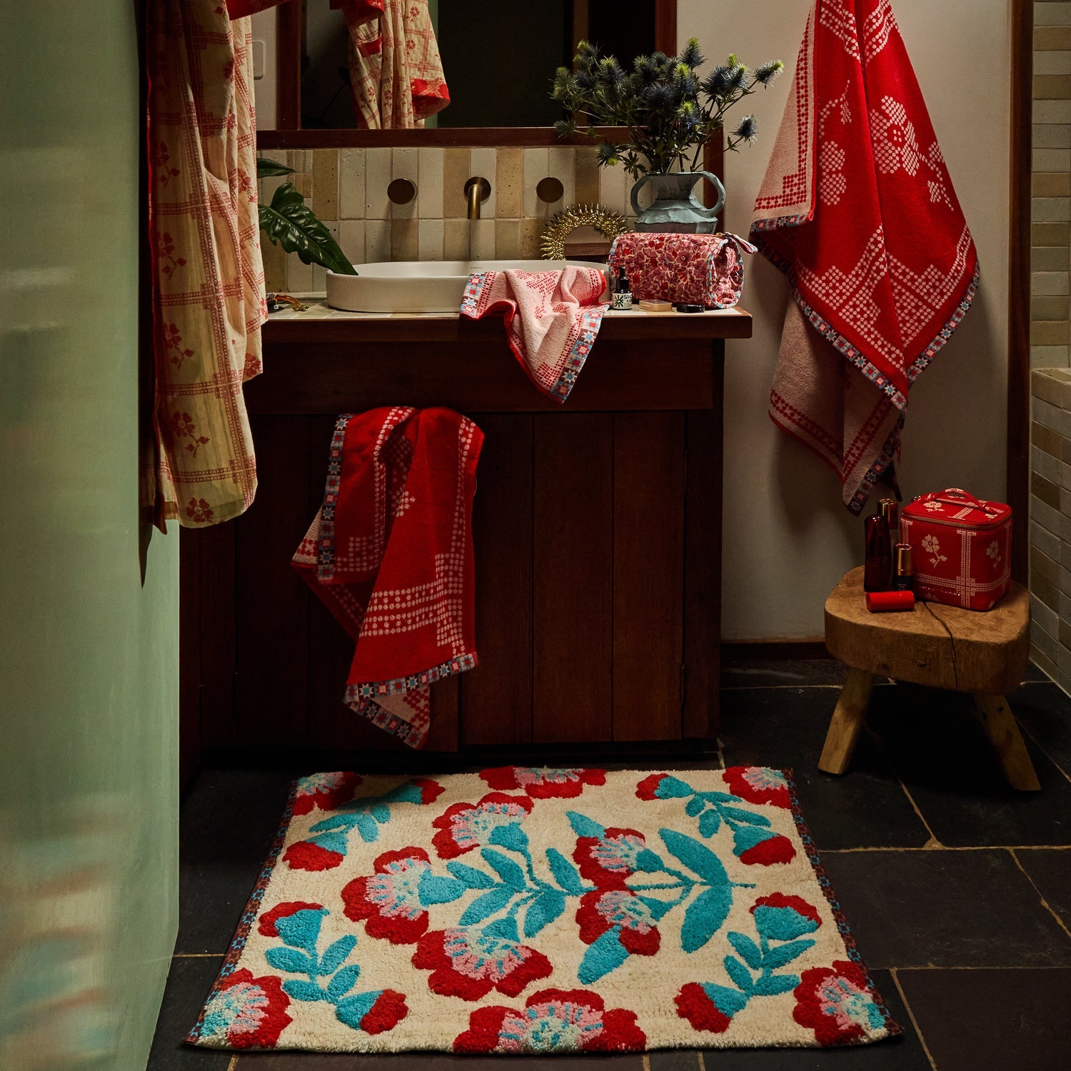 Moonlight Winona Bath Mat with cream ground and red floral tufted design on a dark tiled bathroom floor