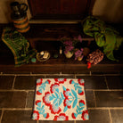 Moonlight Winona Bath Mat on dark stone floor, overhead angle showing cream base with bold red and teal floral tufted pattern
