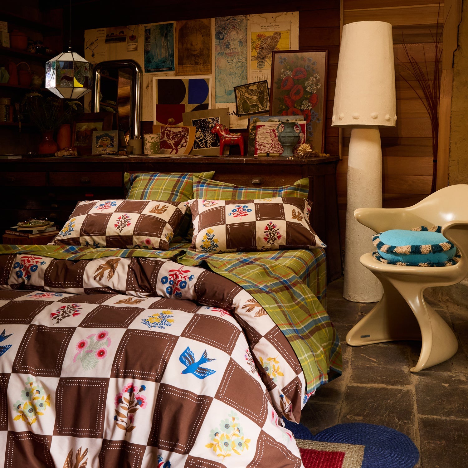 Brown and white checkerboard quilt cover with bird and floral print on a bed in a moody rustic bedroom