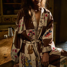 Upper body close-up of cotton robe in brown and cream checkered floral print, showing wide lapels and tied waist belt