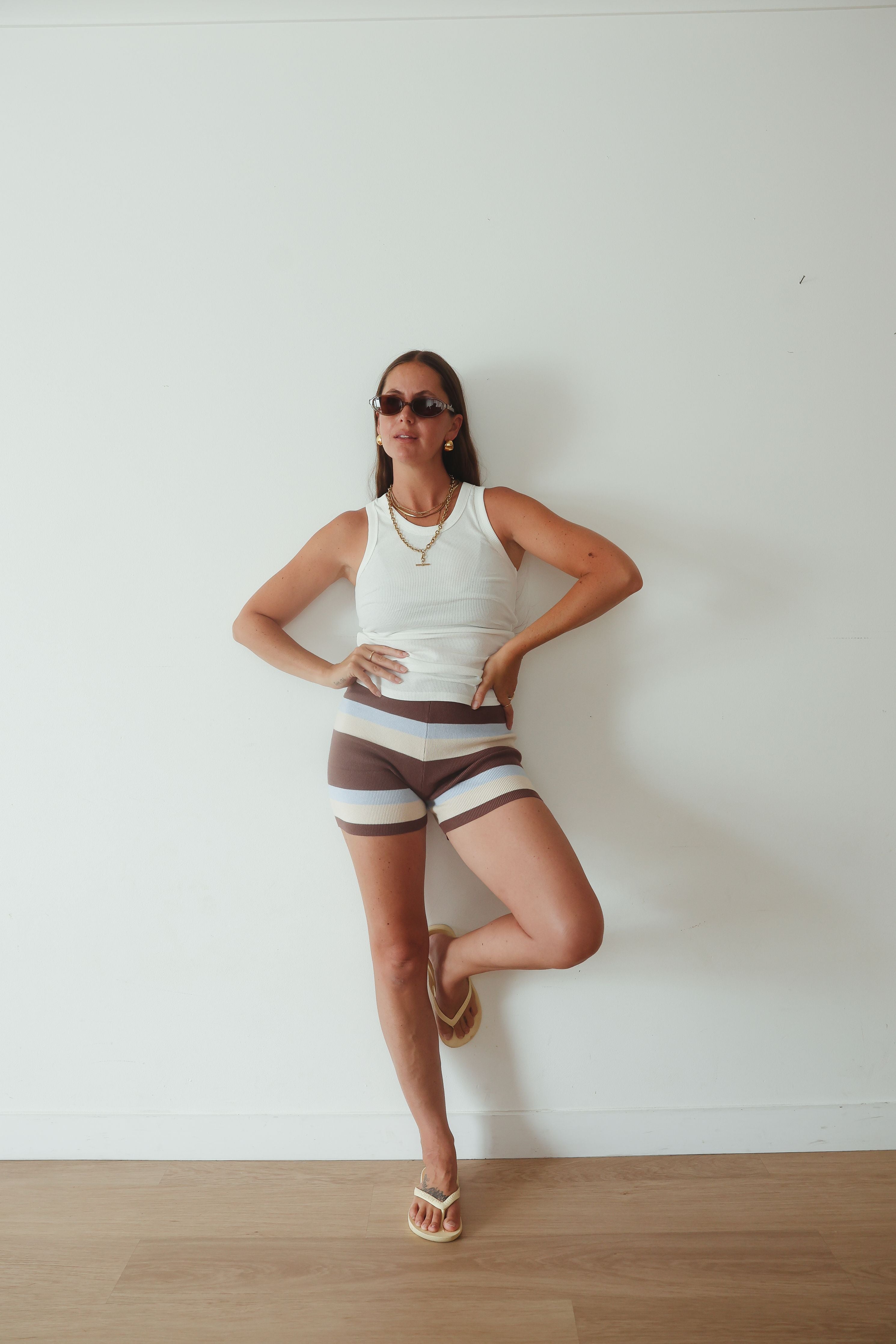Studio angled view highlighting stripe detail on knit shorts in brown, cream and blue colorway