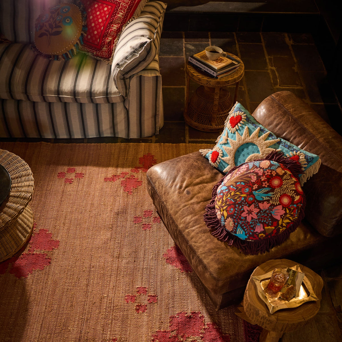 Turquoise tufted sun and moon cushion with fringe trim styled on a leather armchair in a layered living room setting