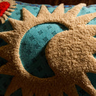 Close-up of cream tufted sun and crescent moon detail on a turquoise patterned cushion cover