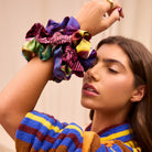Colorful silk scrunchie set worn on wrist showing vibrant purple yellow green multicolor print patterns
