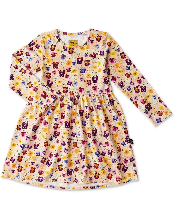 Long sleeve dress covered with pink, purple and yellow pansies on a peach base