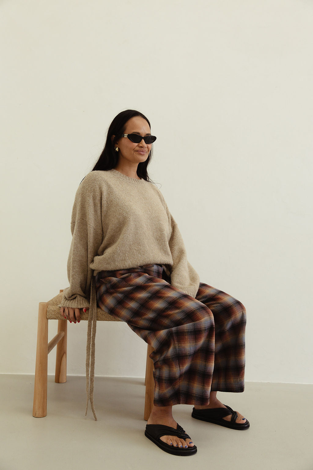 Seated view of Vali check pants displaying brown blue check pattern and wide leg cut